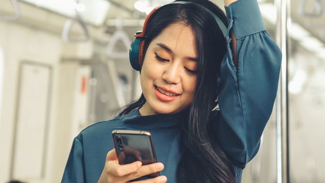 電車の中で音楽を聴く女性