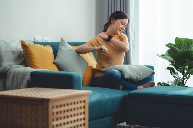 ソファに座り肩を押さえている女性