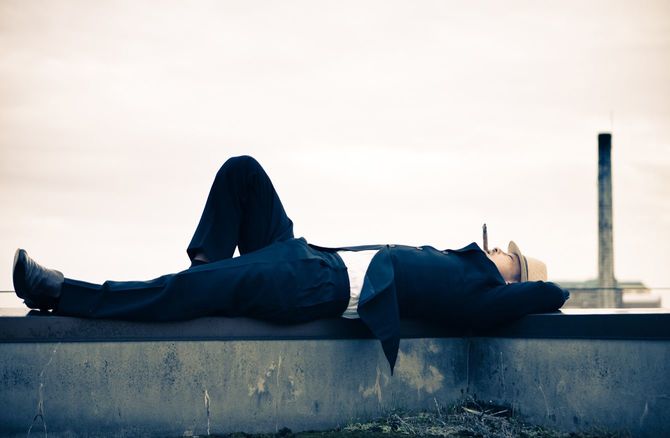 屋上で横たわる男性