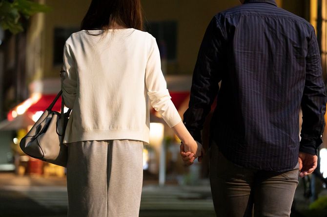 夜の繁華街で手をつないでいる男女