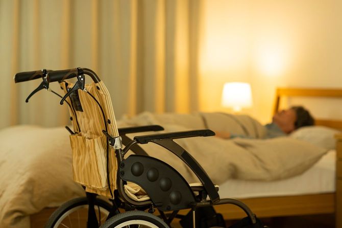 ベッドの横に車いすを置いて寝る人