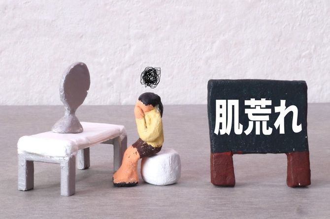 鏡の前で肌荒れに悩んでいる女性