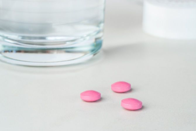 水の入ったコップとピンクの下剤錠