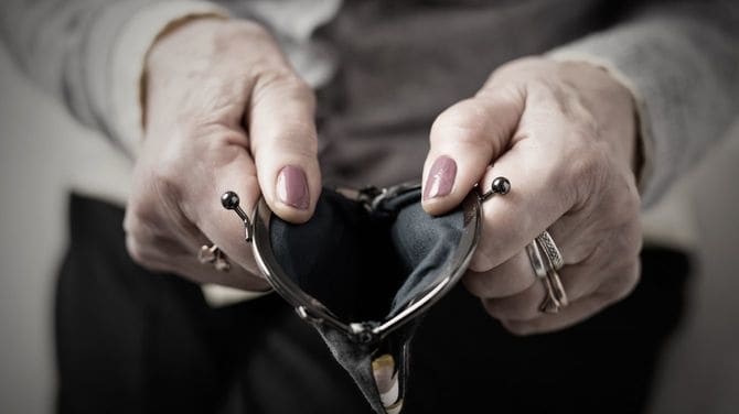 がま口財布を開いて見せるシニア女性の手元