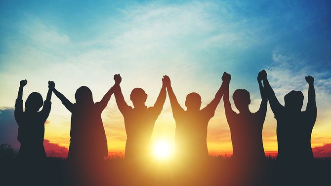 夕日の空に頭の上に高い手を作るグループビジネスチームのシルエット