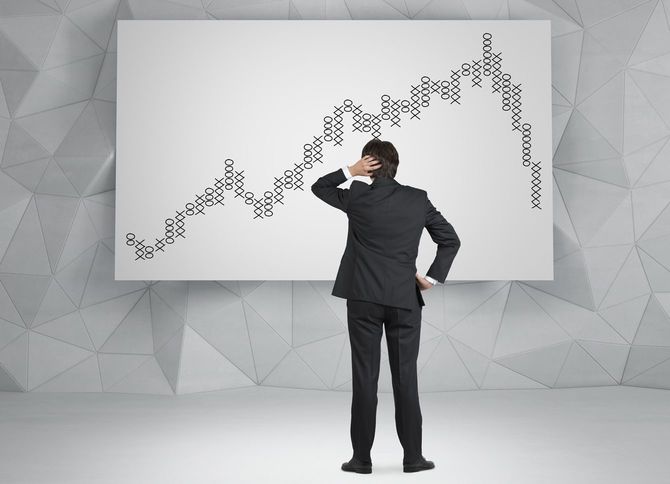 チャートを見つめながら頭をかいている男性