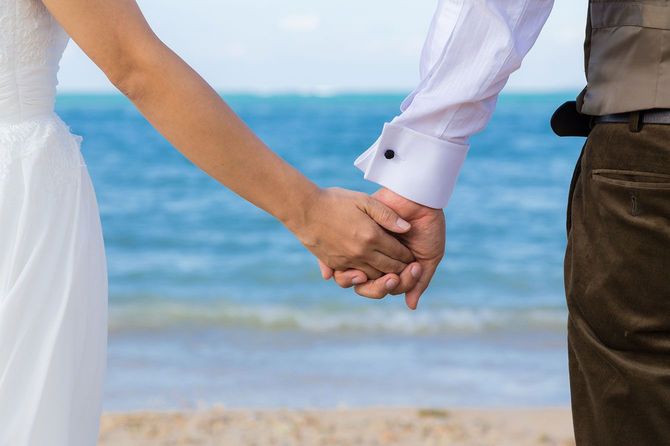リゾートウェディングで手をつなぐカップルの手