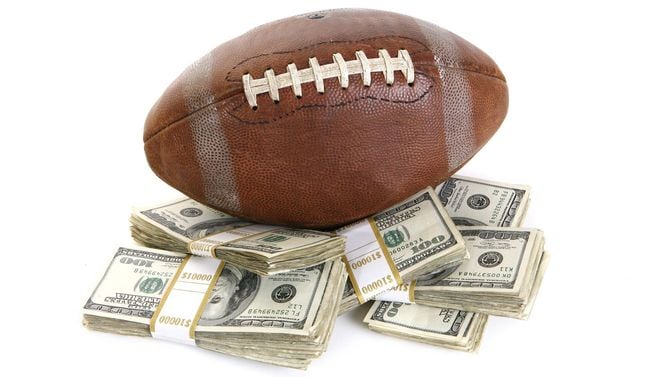 札束の上に置かれたラグビーボール