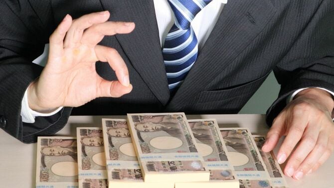 たくさんのお金の前でポーズをとるビジネスマン