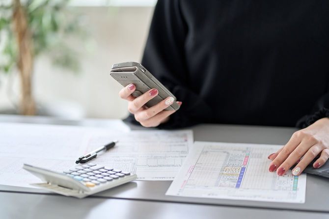 スマートフォンで納税申告書を提出するアジア人女性