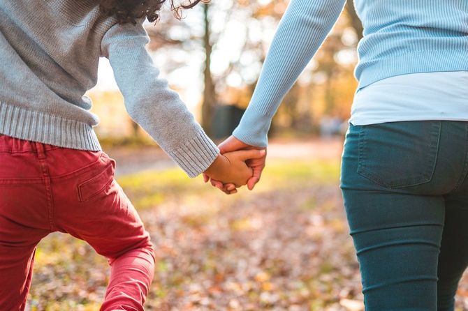美しい秋の日に外を歩きながら手をつないでいる母と息子