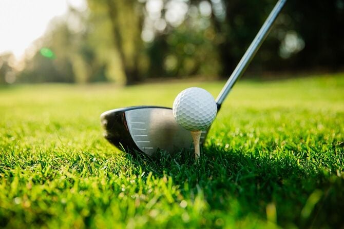 ゴルフコースの緑の芝生の上のゴルフクラブとゴルフボール