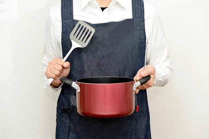エプロンを着て鍋を持っている男