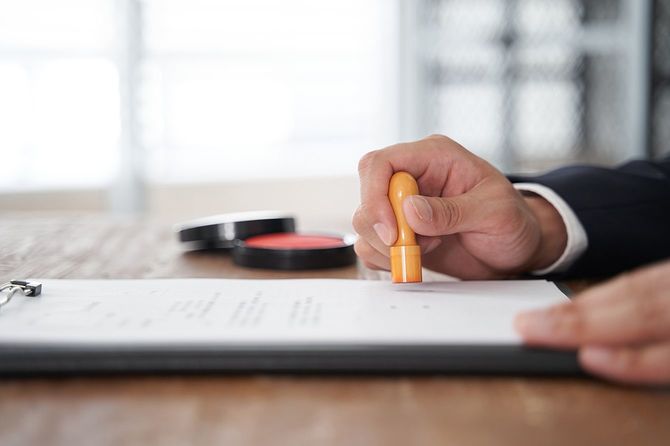 文書に会社の印鑑を押す日本人男性ビジネスマン