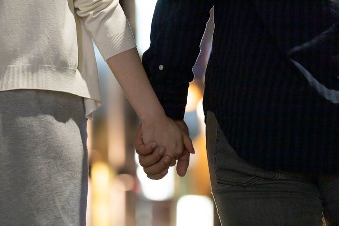 夜の繫華街を手をつないで歩く男女