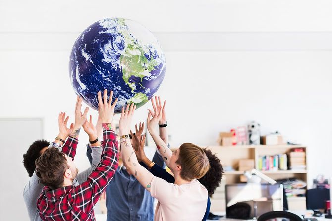 若いビジネスチームが地球儀を持ち上げる