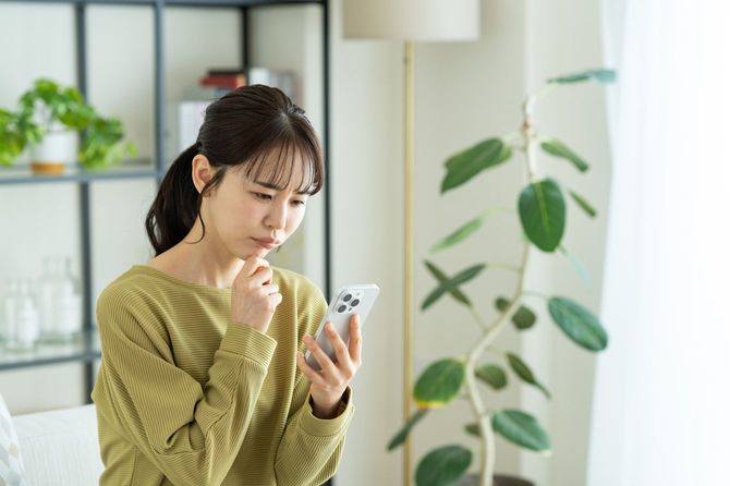スマートフォンを不満げに見つめている女性