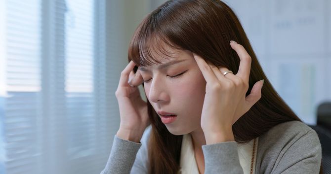 女性が頭痛を感じているワーキングオフィス