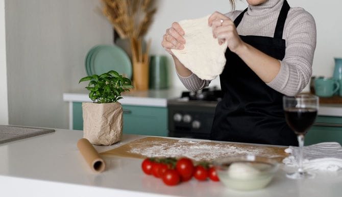 若い妻が台所で生地をこねて夕食を準備しています。