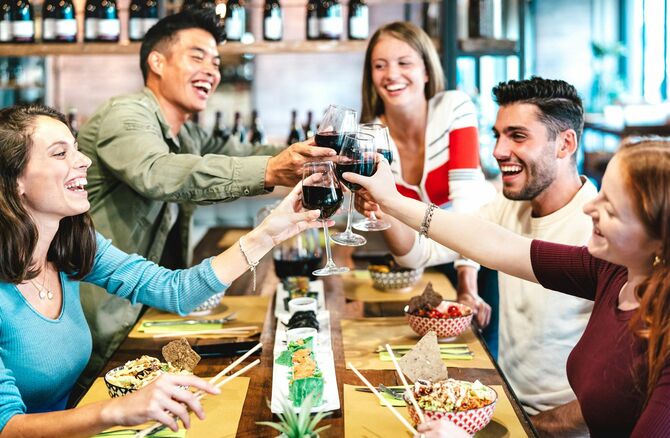 寿司レストランにて赤ワインで乾杯する多民族の人々