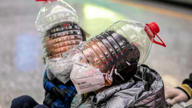 マスクや手袋、ペットボトルを改造したものを装着した少年たち＝2020年2月1日、中国・広州空港