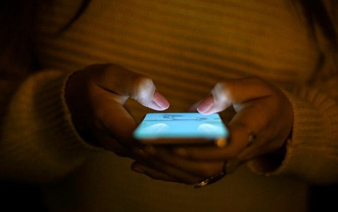 暗闇の中でテキストメッセージを送る女性