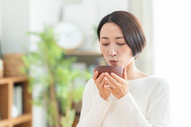 リビングで味噌汁を飲む女性