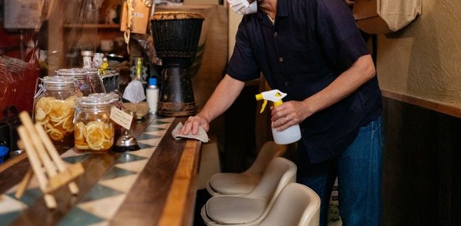 カウンターを念入りにアルコール消毒する店主