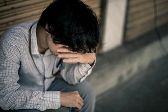 座り込んで額に手を当てる男性