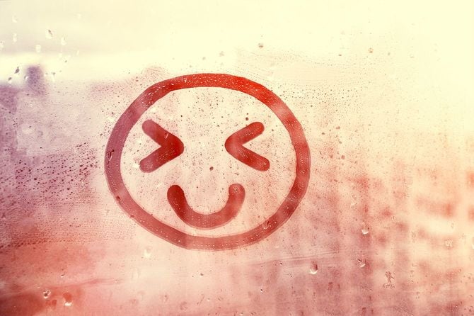 雨滴があふれた窓に描かれた幸せな笑顔