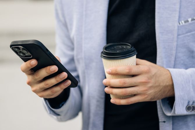 スマホとコーヒーを持つ手