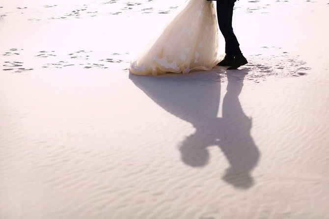 砂浜でキスをする新郎新婦