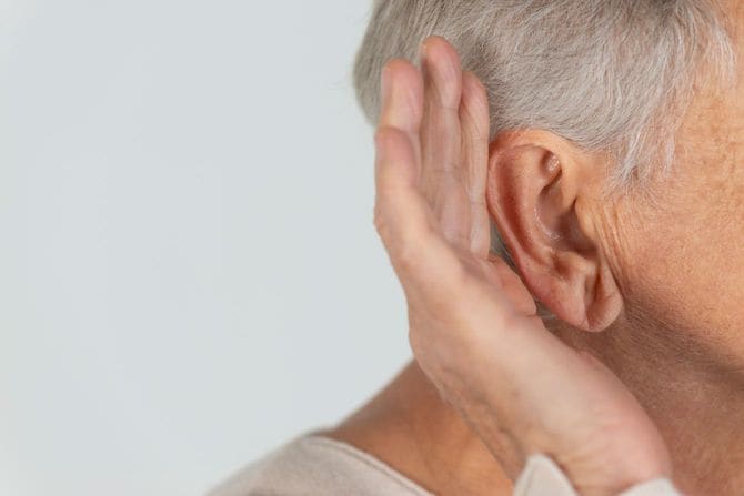 耳に手をあててよく聞こうとする高齢の女性
