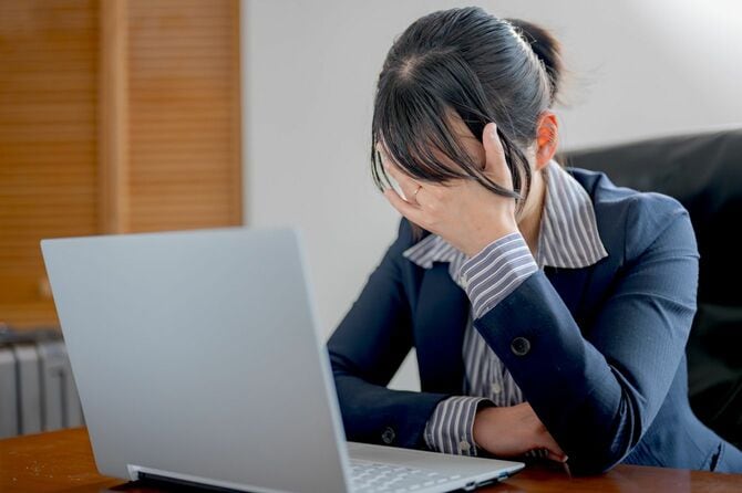 頭をおさえて悩むビジネスウーマン