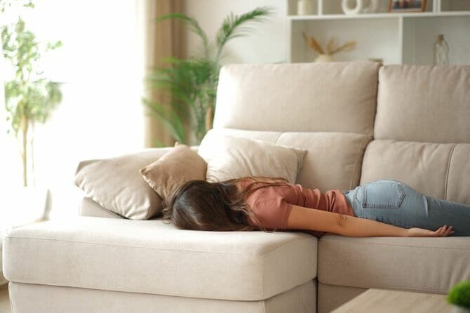 リビングルームのソファに横たわる疲れた女性