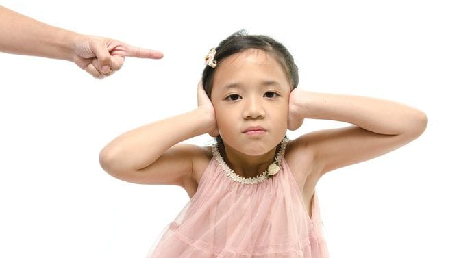 叱る母親と耳をふさぐ少女