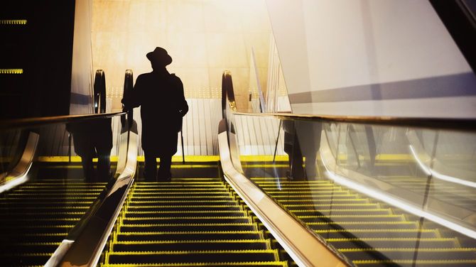 エスカレーターで降りる男性