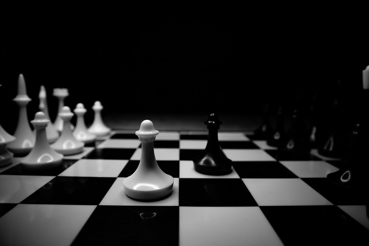 チェス盤に載っている白と黒のチェスの駒
