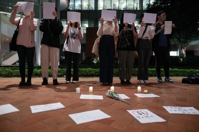 2022年11月29日、香港の香港大学で行われた中国のゼロコロナ政策の犠牲者と、新疆ウイグル自治区の首都ウルムチ火災の犠牲者への追悼集会で、白紙のプラカードを手にする学生たち。