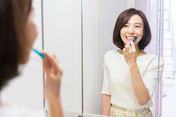 鏡を見ながら歯磨きをする女性