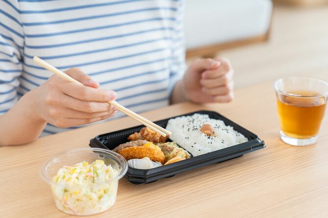 コンビニ弁当を食べる若い女性
