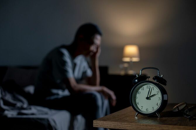 不眠に悩む男性と目覚まし時計