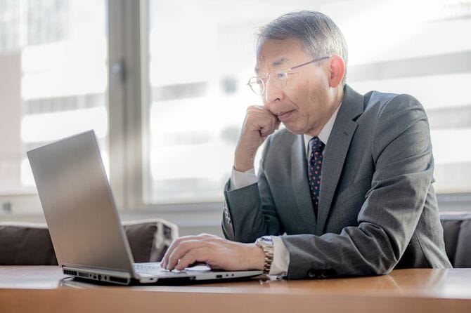 PCを前に思案する熟年ビジネスマン